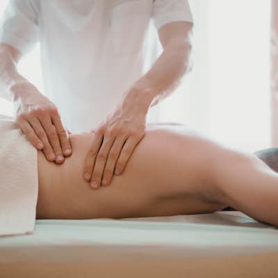 An unrecognizable masseuse giving a relaxing massage to an anonymous woman lying face down on the bed.