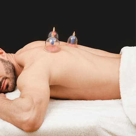 Health recovery man with vacuum cups. Closeup of vacuum cups on man's back on black background. Traditional oriental medicine.