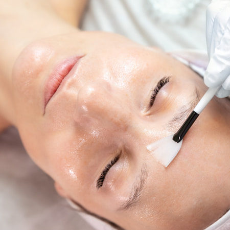 Close-up beautician doctor hand making anti-age procedure apply peeling acid young attractive female client at beauty clinic. Cosmetologist specialist doing skincare treatment. Health care therapy.