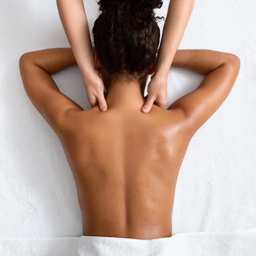 Female therapist massaging black woman neck, top view, spa concept


