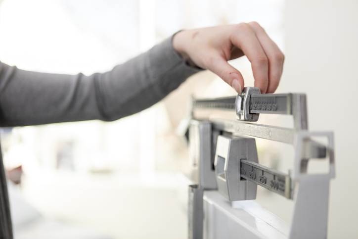 Close Up Unrecognizable Woman Adjusting Beam Scale In Doctor's Examination Room
