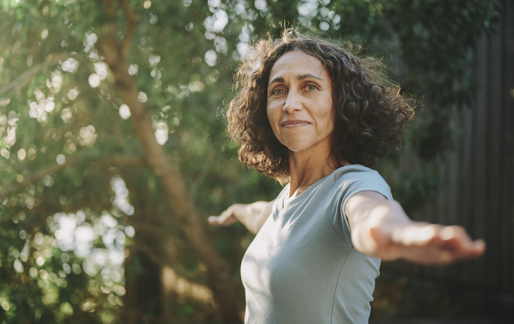Smiling Mature Woman Doing Yoga Outside In A Park In Summer