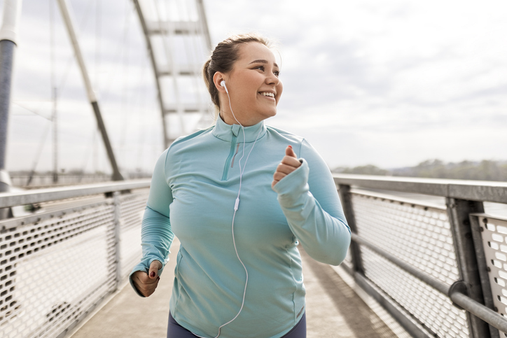 Overweight Young Woman Running Across Bridge